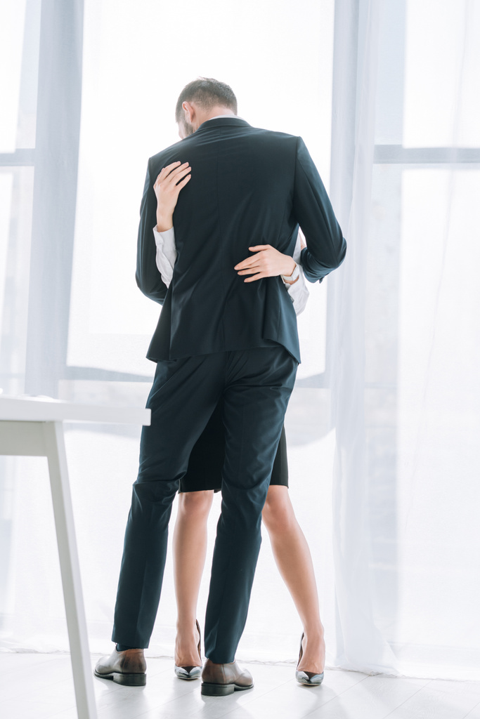 back view of businessman in suit hugging secretary in office  - 写真・画像