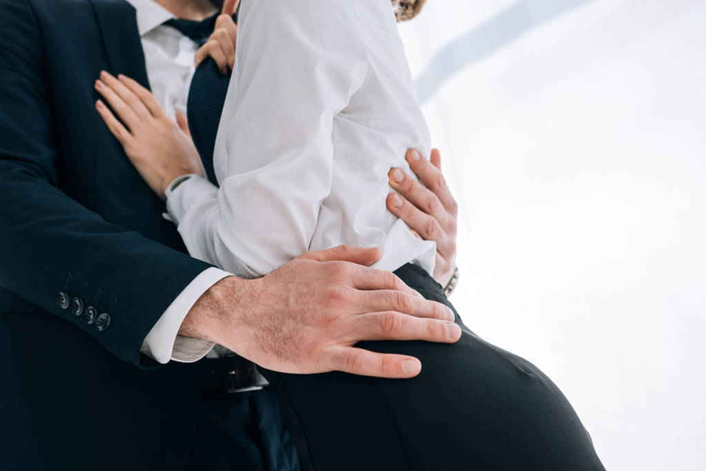 visão cortada de homem de negócios em terno abraçando secretário no escritório
  - Foto, Imagem