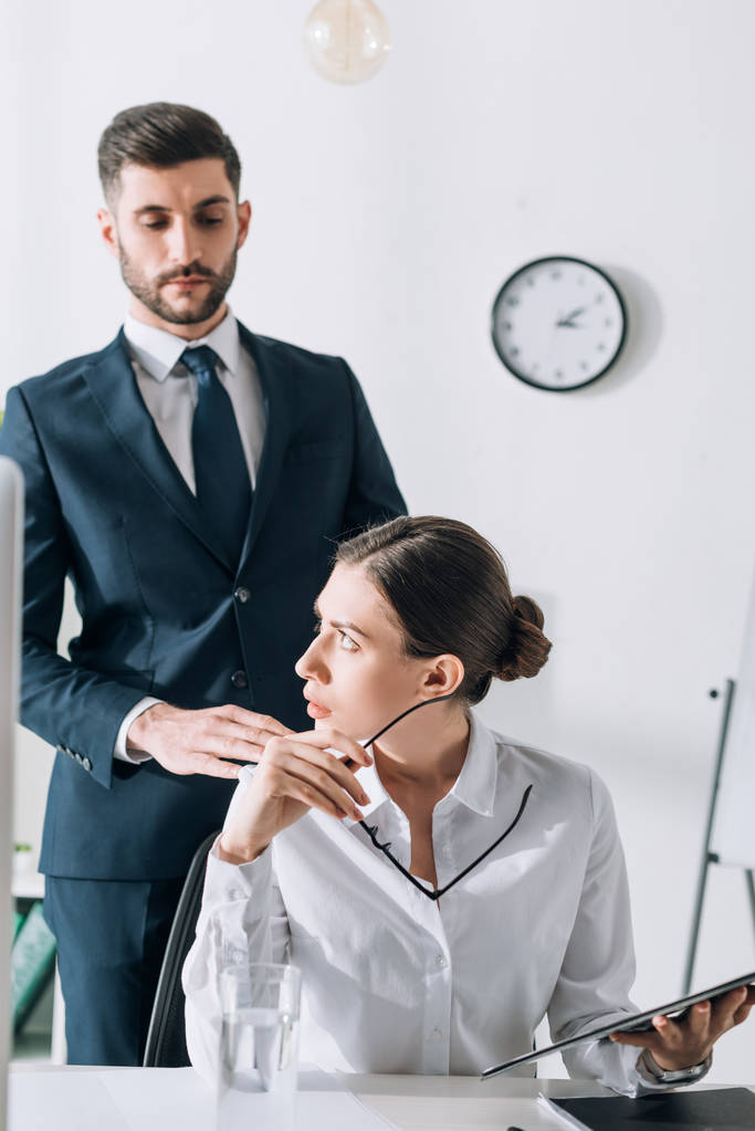 schöner Geschäftsmann im Anzug berührt schockierte Geschäftsfrau im Amt  - Foto, Bild