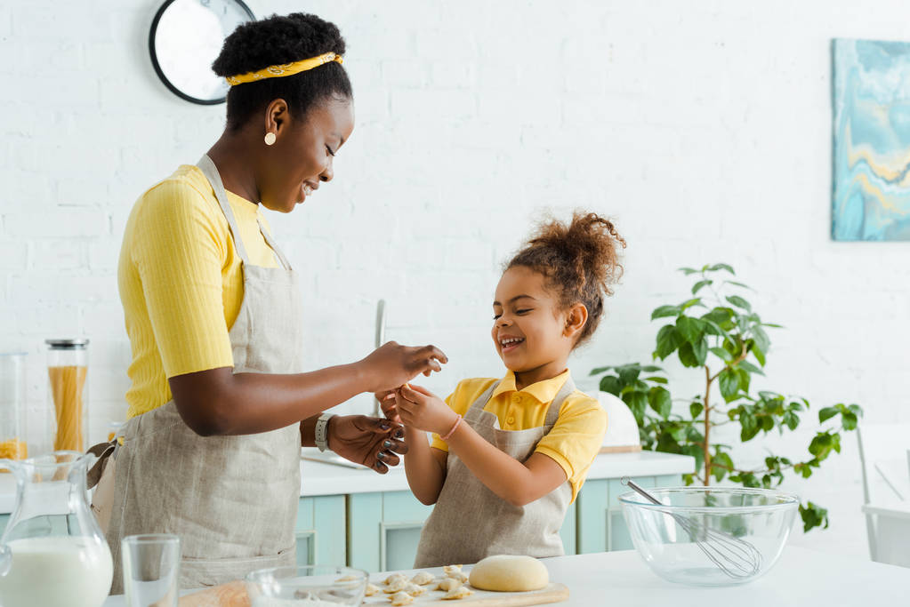 boldog afro-amerikai anya és lánya faragás nyers tészta főzés közben gombóc  - Fotó, kép