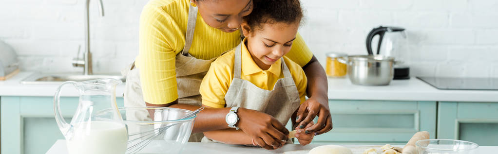 panoraama laukaus onnellinen afrikkalainen amerikkalainen äiti lähellä söpö tytär veistämällä nyytit keittiössä
  - Valokuva, kuva