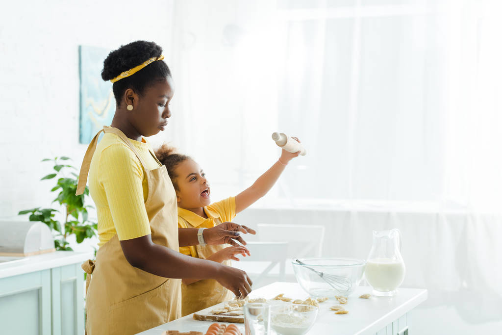 attrayante mère afro-américaine près de fille mignonne tenant rouleau à pâtisserie
  - Photo, image