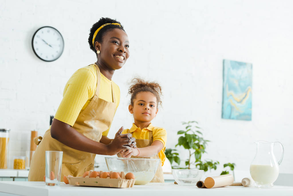 africano americano bambino e allegra madre sorridente mentre cucina in cucina
  - Foto, immagini