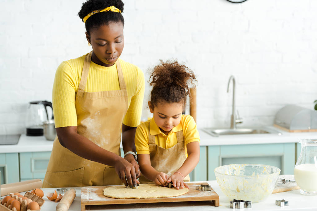 adorable african american kid and mother holding cookie cutters near raw dough  - 写真・画像