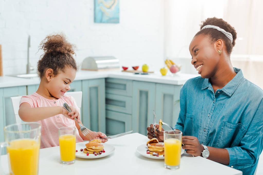 felice madre afro-americana guardando figlia vicino gustosi pancake
  - Foto, immagini