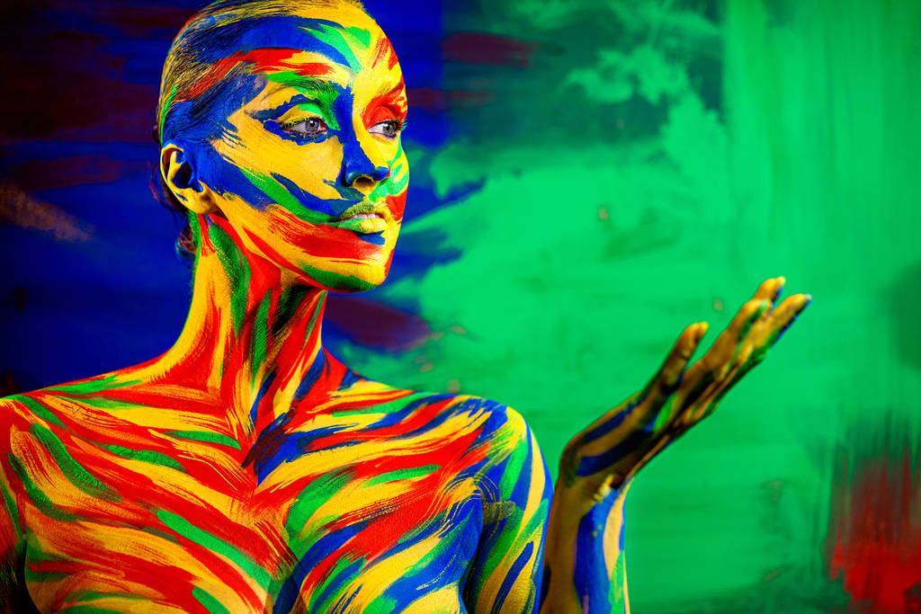 Color art face for inspiration. Abstract portrait of the bright beautiful girl with colorful make-up and bodyart. Woman pointing to looking right. - Photo, Image