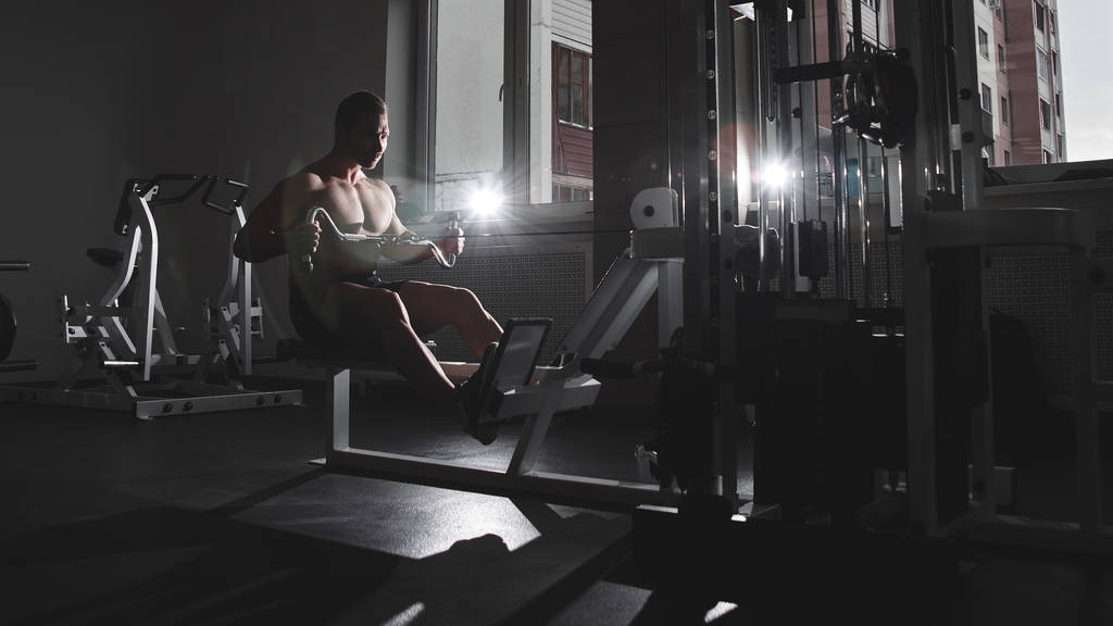 Портрет спортсмена с мускулистым телом делает упражнения на спортивном инвентаре в тренажерном зале, тренировочные мышцы рук, накачивание бицепсов и трицепсов
 - Фото, изображение