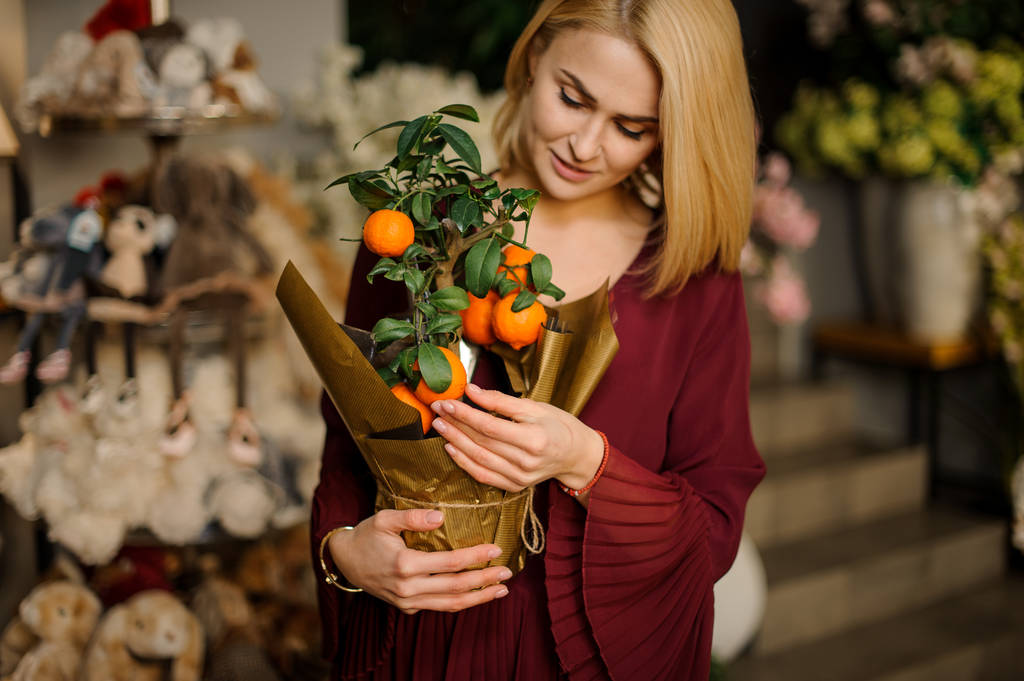 Mooie vrouw met mandarijnboom in pot - Foto, afbeelding