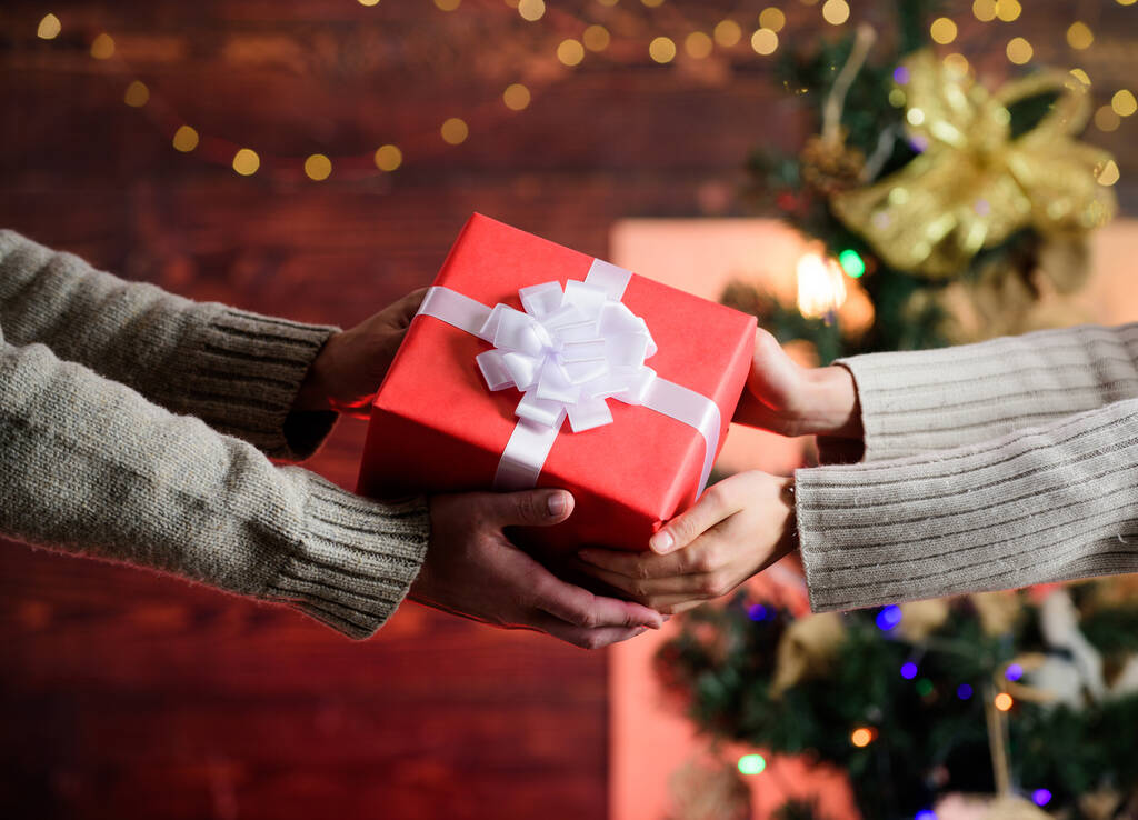 配送サービス。ギフトボックスを持っている手。郵便局だ。最も近いと共有します。手にギフトボックスを閉じます。ハンドオーバーの概念。クリスマスは弓で贈り物を包んだ。愛を広めて。与えること・受けること - 写真・画像
