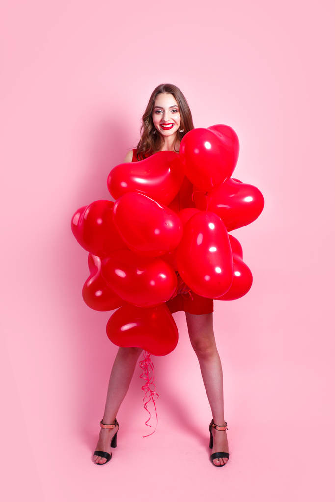 Pembe arka planda kırmızı kalp hava balonları olan moda kızı.. - Fotoğraf, Görsel