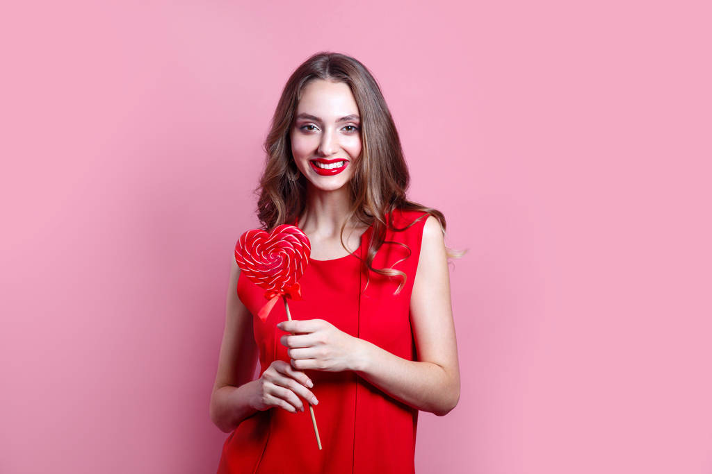 Portrait belle femme avec sucette rouge sur fond rose coloré
 - Photo, image