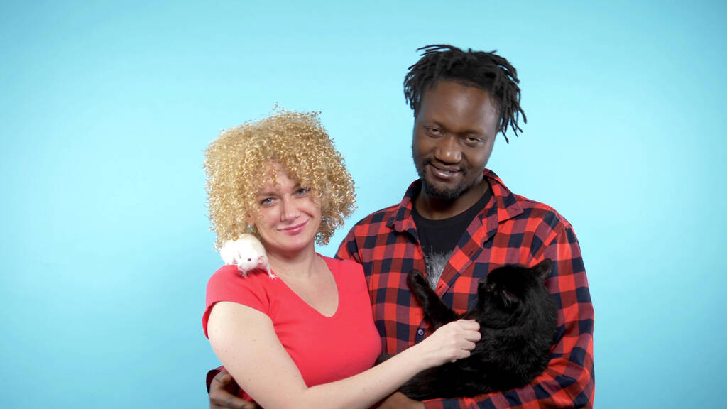  Homme africain et femme caucasienne. tenant un chat noir et un rat blanc
.  - Photo, image