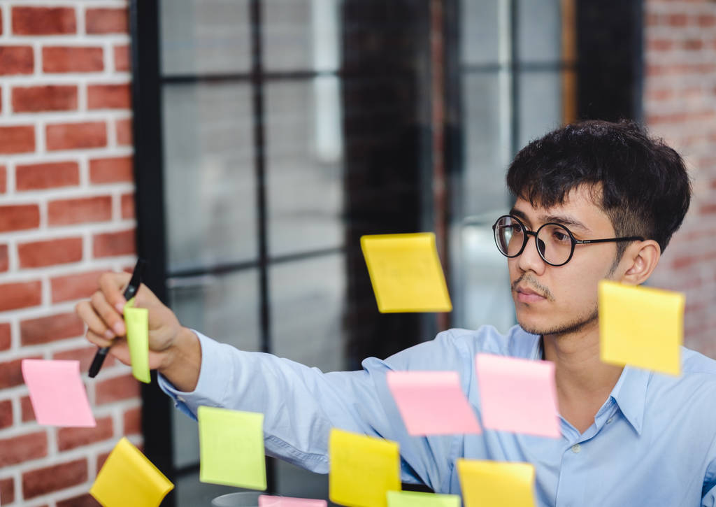 asian businessman looking and writing on sticky note for brainst - Photo, Image