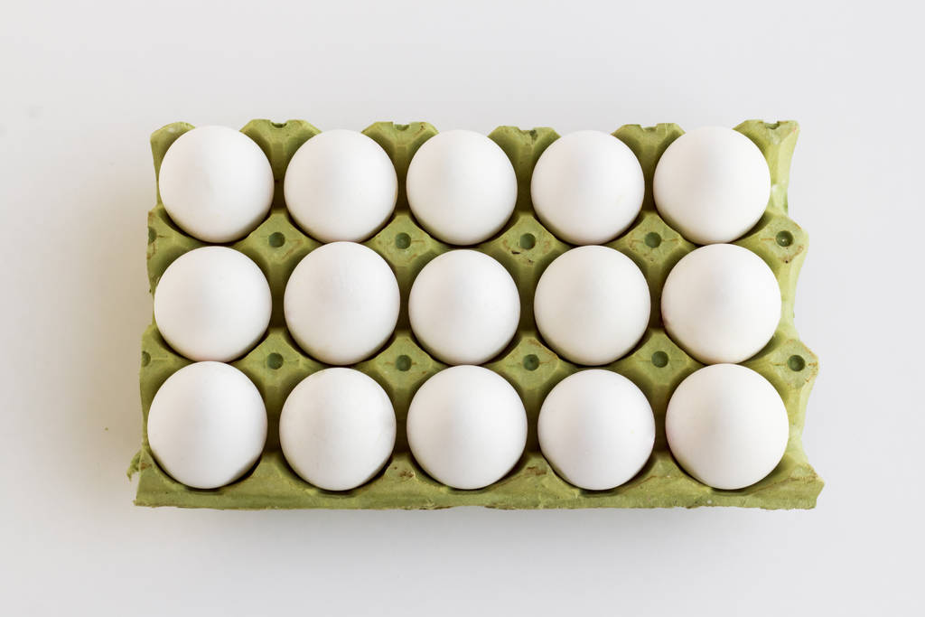 lähikuva raakojen kananmunien pakkauksesta valkoisella pinnalla
 - Valokuva, kuva
