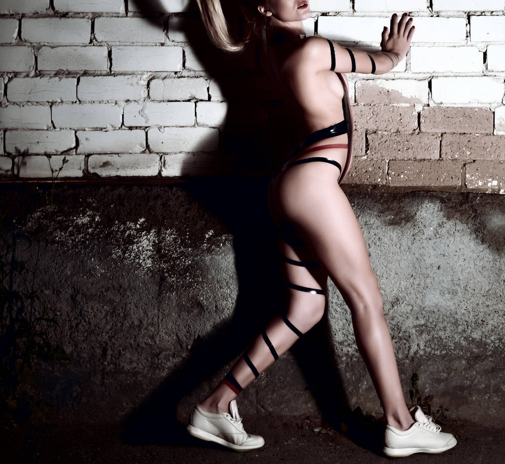 Seksi kadın yarı çıplak vücut. genç kadın kılığında. Tuğla duvar doku üzerinde dramatik gölge  - Fotoğraf, Görsel