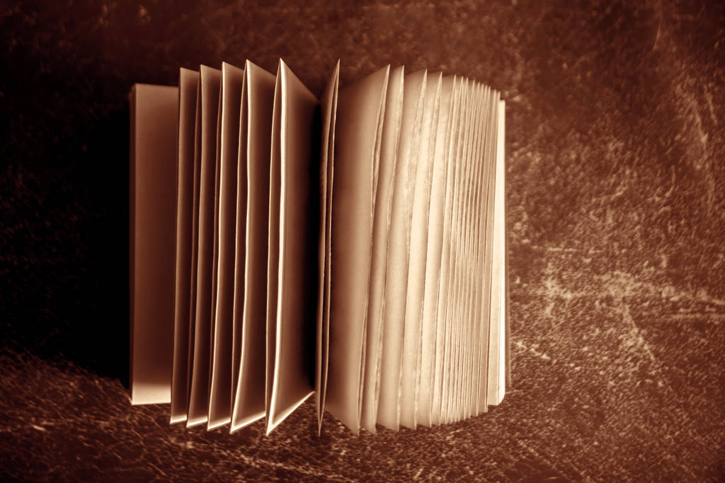 παλιό ανοιχτό φθαρμένο βιβλίο top view σε μαύρο και άσπρο δερμάτινο φόντο.  - Φωτογραφία, εικόνα