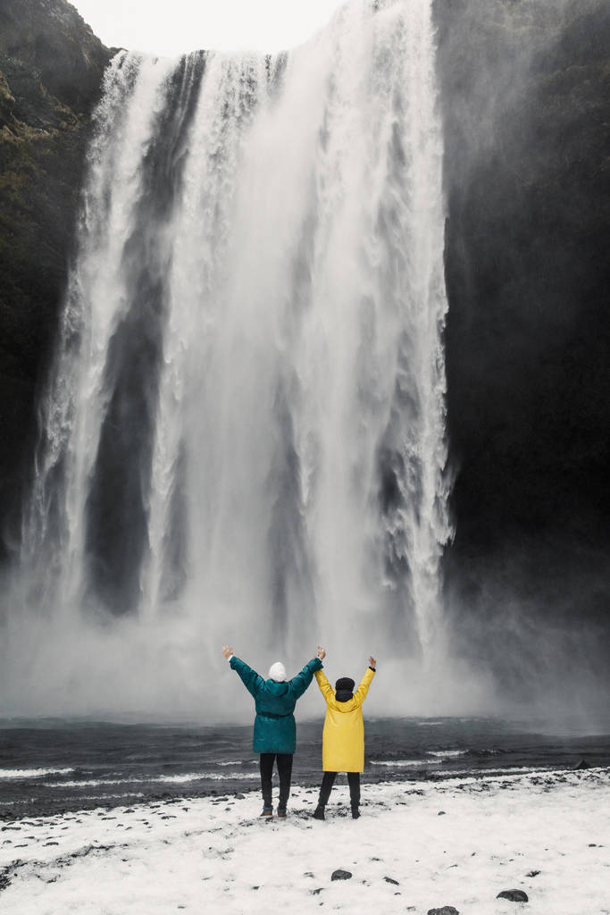 glückliches und lustiges Paar genießt großen Wasserfall vor dem Hintergrund der isländischen Berge - Foto, Bild