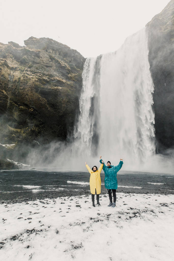 gelukkig en grappig paar genieten van grote waterval met in IJsland bergen achtergrond - Foto, afbeelding