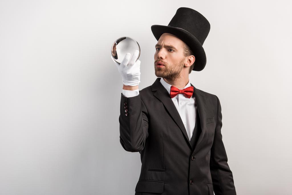interested professional magician holding magic ball, isolated on grey - Photo, Image