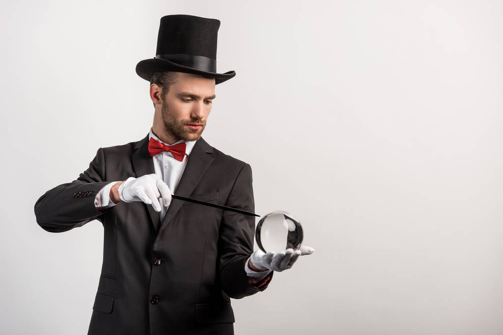 professional magician holding wand and magic ball, isolated on grey - Photo, Image
