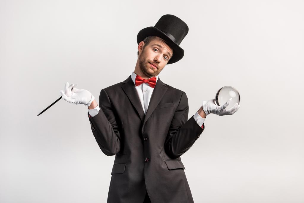 goochelaar met schouderophalen stok en magische bal, geïsoleerd op grijs - Foto, afbeelding