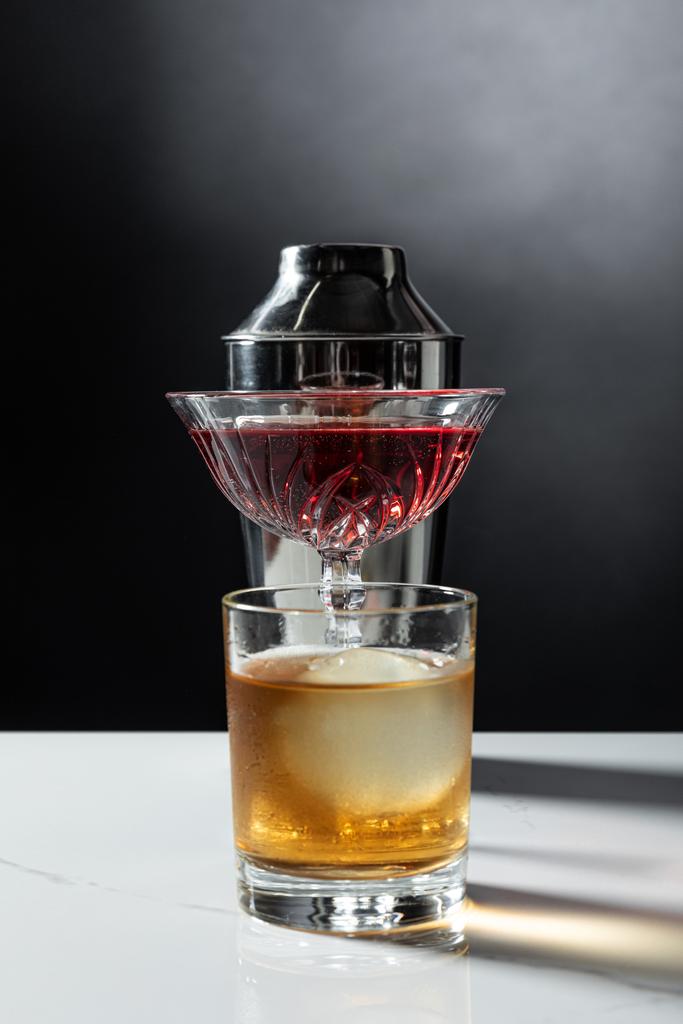 Glas Whisky in der Nähe von Rotwein und Shaker auf schwarz mit Rauch  - Foto, Bild