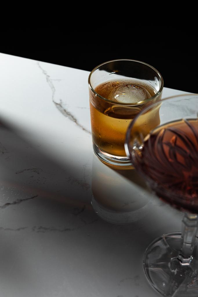 seçici cam odağı, kırmızı şarap yanında viski, siyah üzerine izole.  - Fotoğraf, Görsel