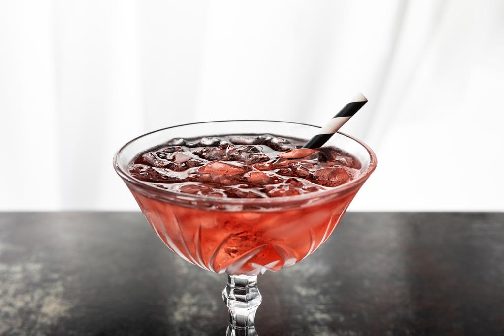 red cocktail with striped straw and ice cubes on white  - Photo, Image