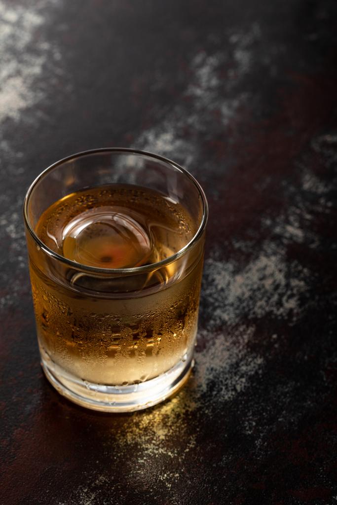 vaso con whisky fuerte y cubo de hielo en la superficie negra
  - Foto, Imagen