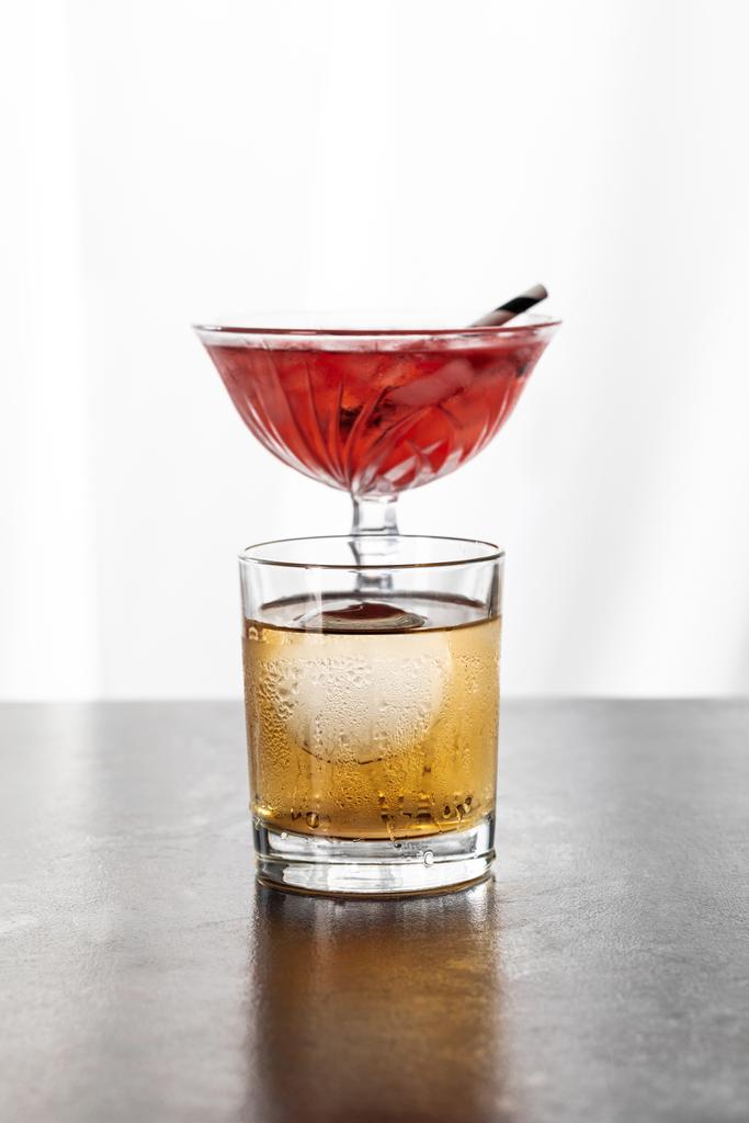 mokre szkło z whiskey w pobliżu czerwonego koktajlu kosmopolitycznego na białym  - Zdjęcie, obraz