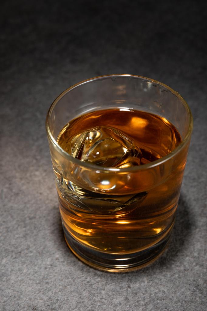 jääkuutiot lasillisessa alkoholijuomaa harmaalla pinnalla
  - Valokuva, kuva