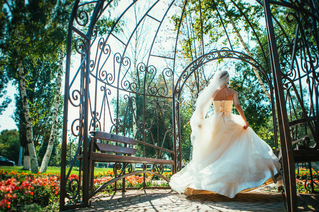 Junge schöne Braut steht in einem Pavillon im Park - Foto, Bild