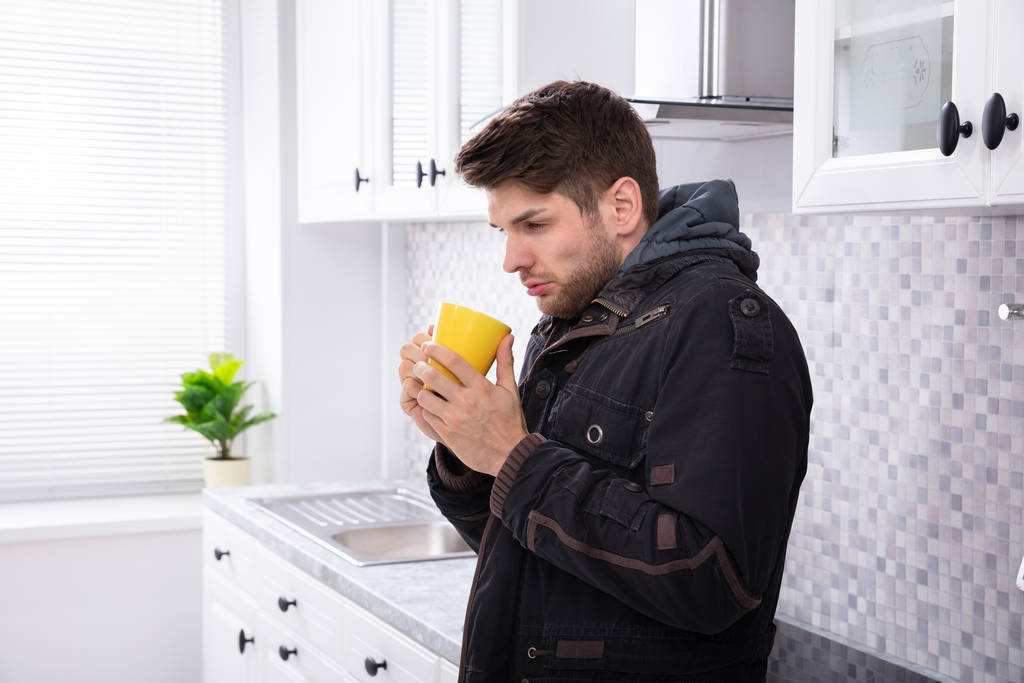 Side View sairaan miehen juominen kahvia seisoo keittiössä
 - Valokuva, kuva