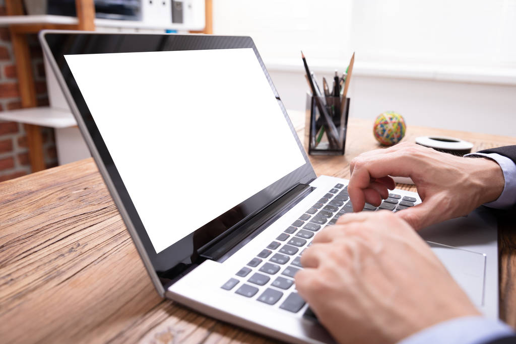 Рука бизнесмена касаясь ноутбука с чистым белым экраном
 - Фото, изображение