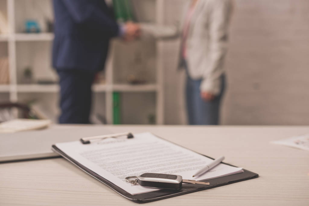 selective focus of clipboard with document on desk near car key and two people shaking hands  - Photo, Image