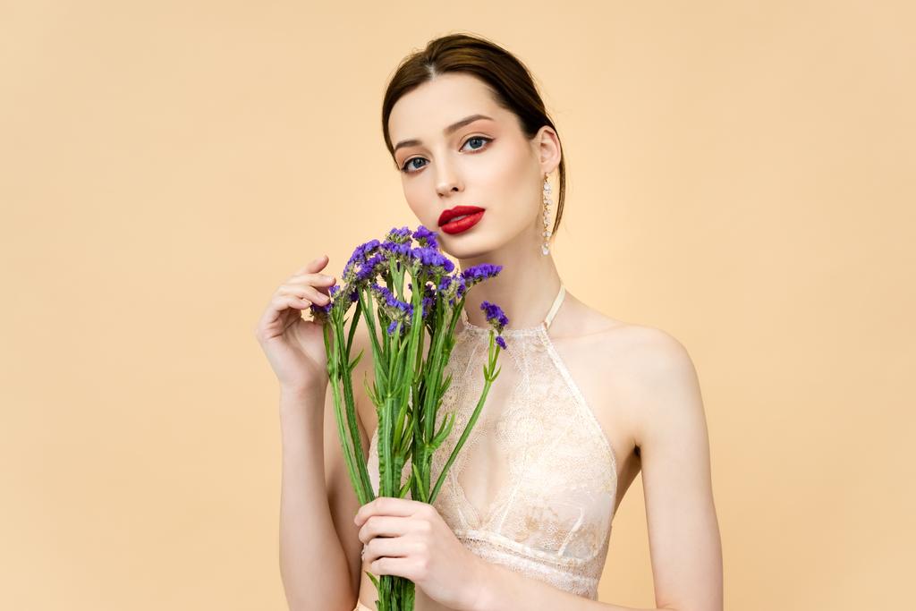 young beautiful woman holding purple limonium flowers isolated on beige  - 写真・画像
