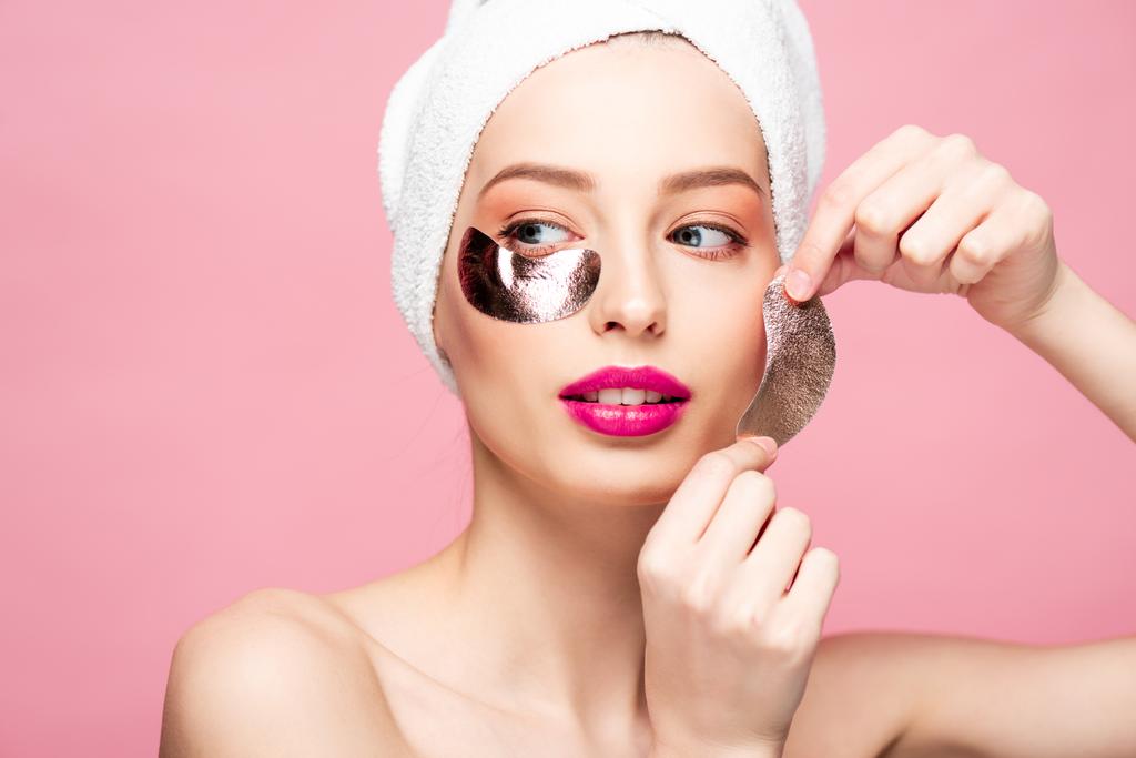 naked young woman in towel applying eye patches isolated on pink  - Fotoğraf, Görsel