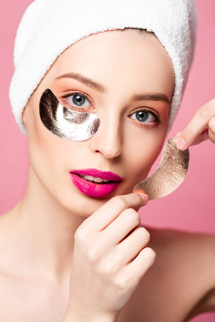 όμορφη γυναίκα σε ενώ πετσέτα εφαρμογή μπαλώματα μάτι απομονώνονται σε ροζ  - Φωτογραφία, εικόνα