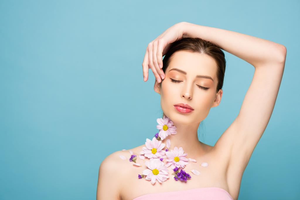 young woman with flowers on neck and closed eyes isolated on blue  - Photo, Image