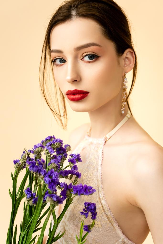 junge attraktive Frau mit Limoniumblüten isoliert auf beige  - Foto, Bild