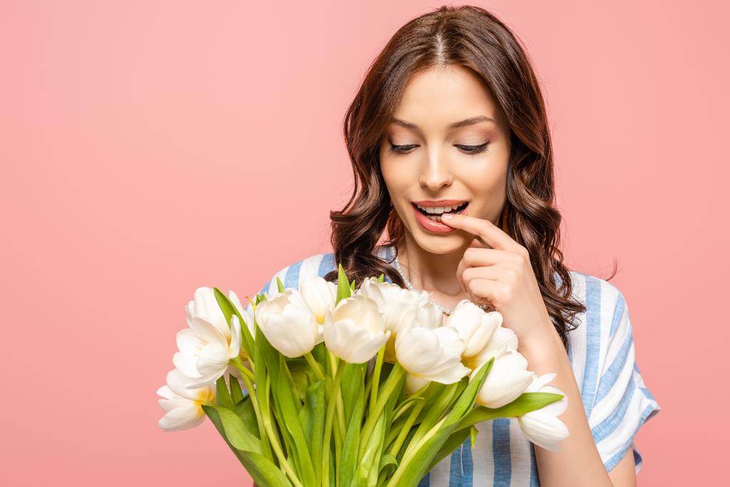 chica feliz tocando el labio mientras sostiene ramo de tulipanes blancos aislados en rosa
 - Foto, Imagen