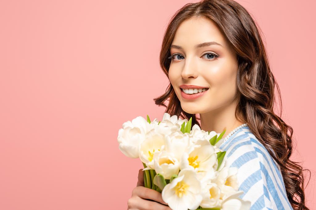  boldog lány gazdaság csokor fehér tulipán, miközben mosolyog a kamera elszigetelt rózsaszín - Fotó, kép