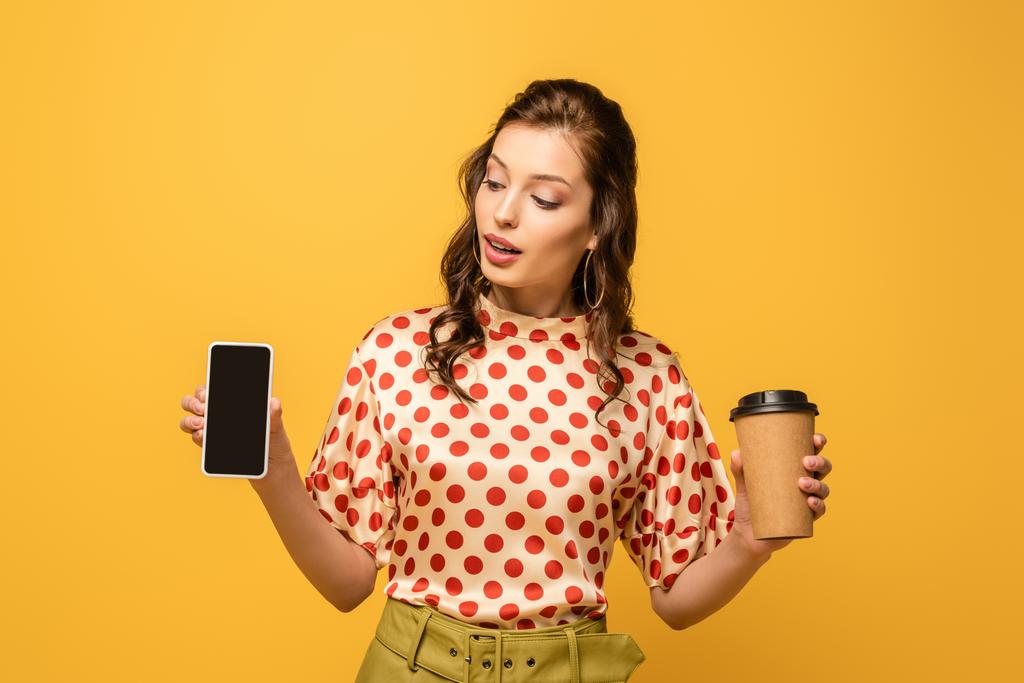 コーヒーを飲みに行く魅力的な若い女性と黄色に隔絶された空白の画面を持つスマートフォン - 写真・画像