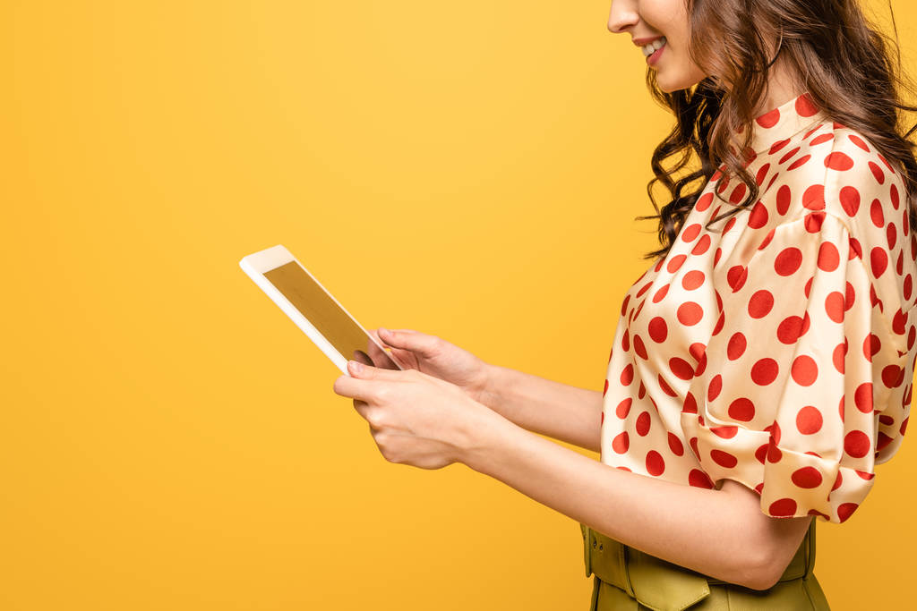 cropped view of smiling young woman using digital tablet isolated on yellow - Photo, Image