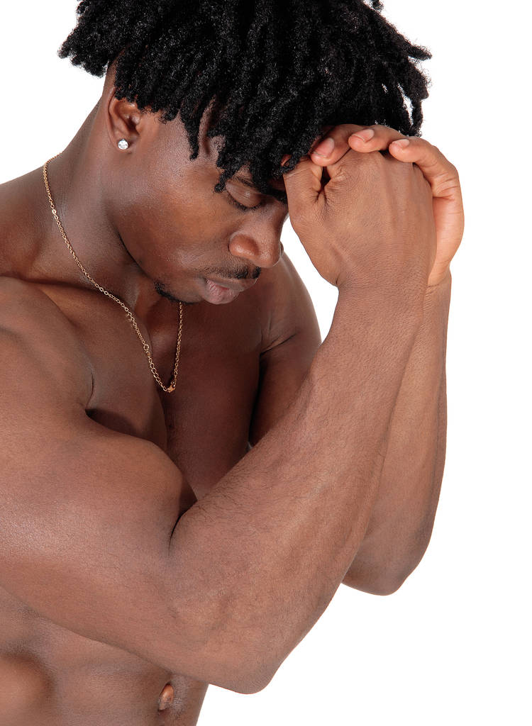 Un hombre afroamericano que flexiona sus músculos con sus puños en su frente y los ojos cerrados, aislado por fondo blanco.. - Foto, imagen