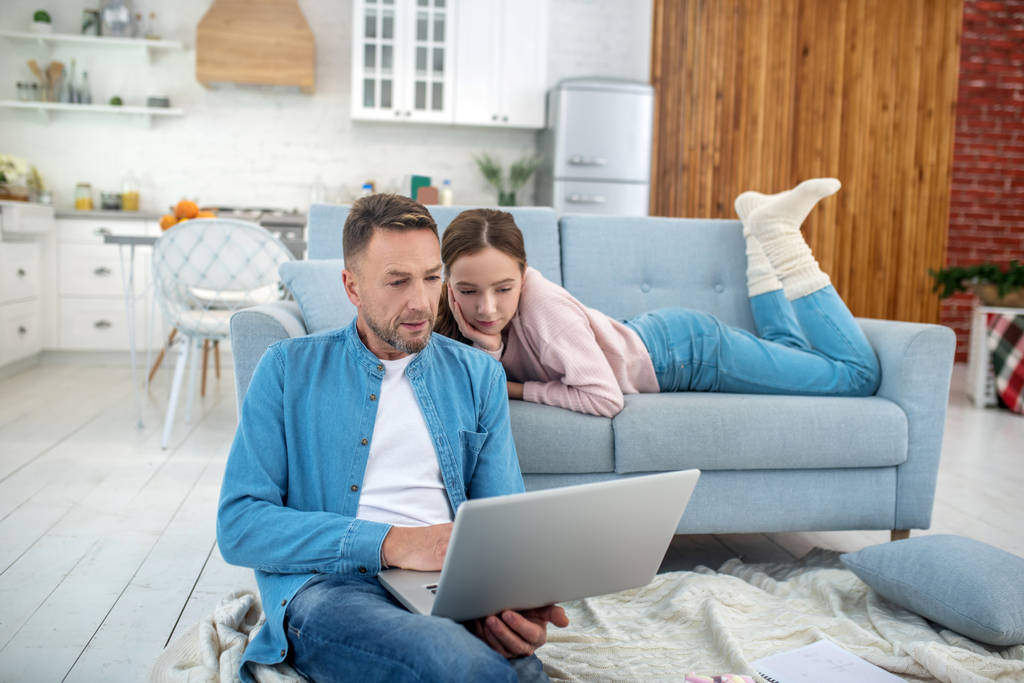 Vader en dochter in goed humeur laptop kijken thuis. - Foto, afbeelding