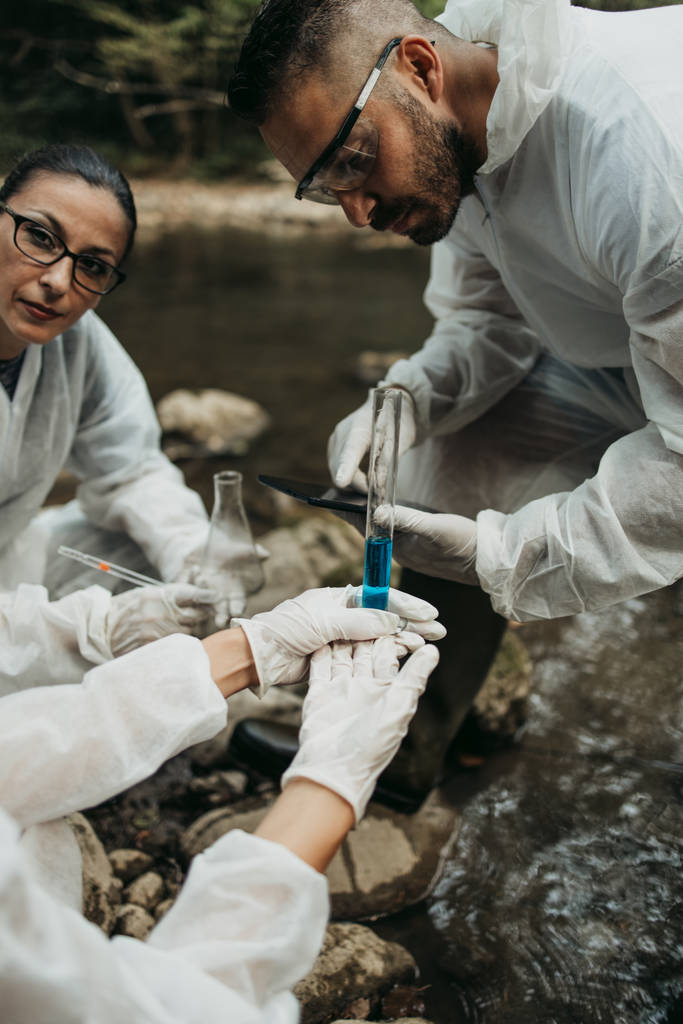 Equipo de científicos y biólogos investigando las posibilidades de propagación de bacterias y virus a través de suministros naturales de agua corriente para beber. - Foto, imagen