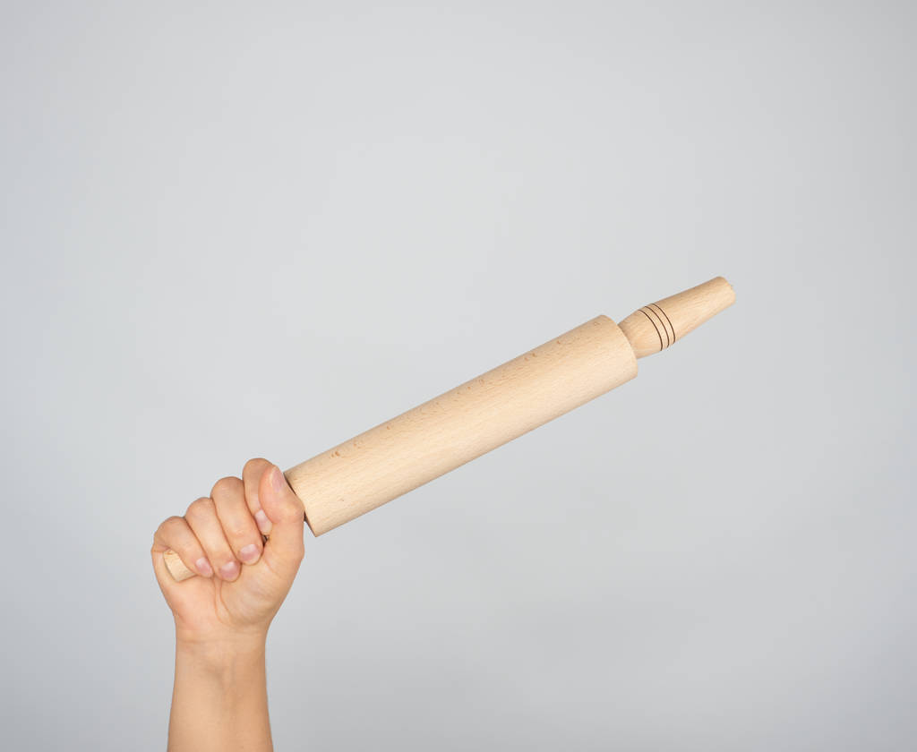 hand holding a wooden rolling pin on a gray background - Photo, Image