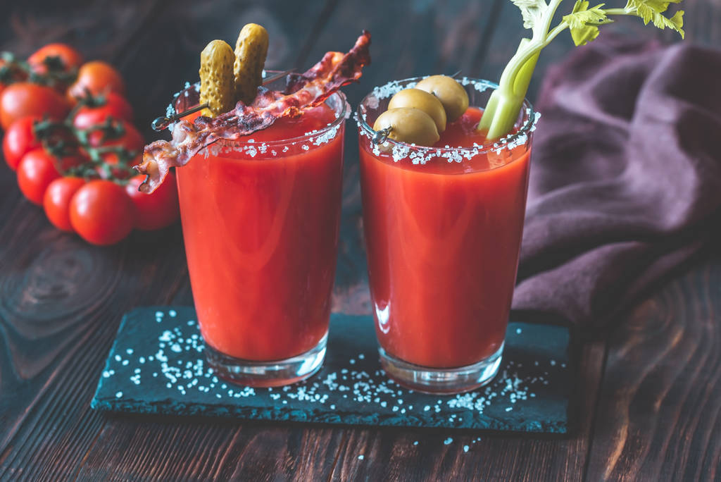 Dvě sklenice Bloody Mary zdobené okurkami, smaženými slaninovými proužky, zelenými olivami a celerovým stonkem - Fotografie, Obrázek