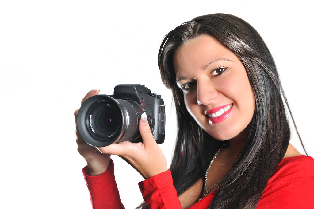 Mujer joven sosteniendo la cámara en la mano tomando fotos aisladas
 - Foto, imagen